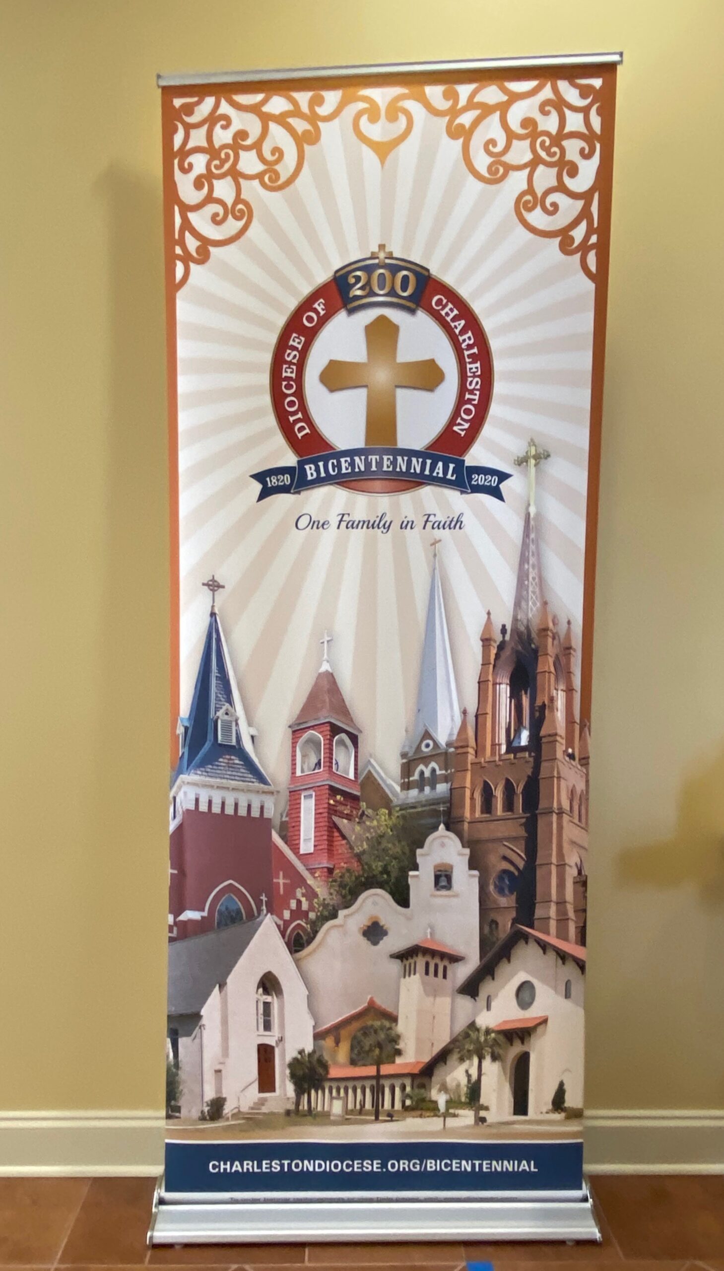 bicentennial banner with churches and a gold cross in a red boarder